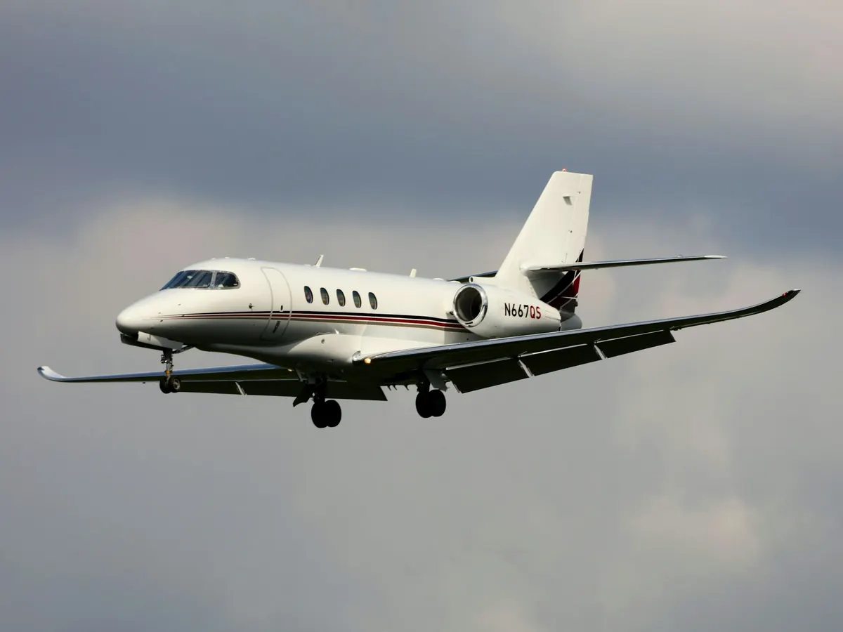 Midsize business jet with gear down against grey cloud