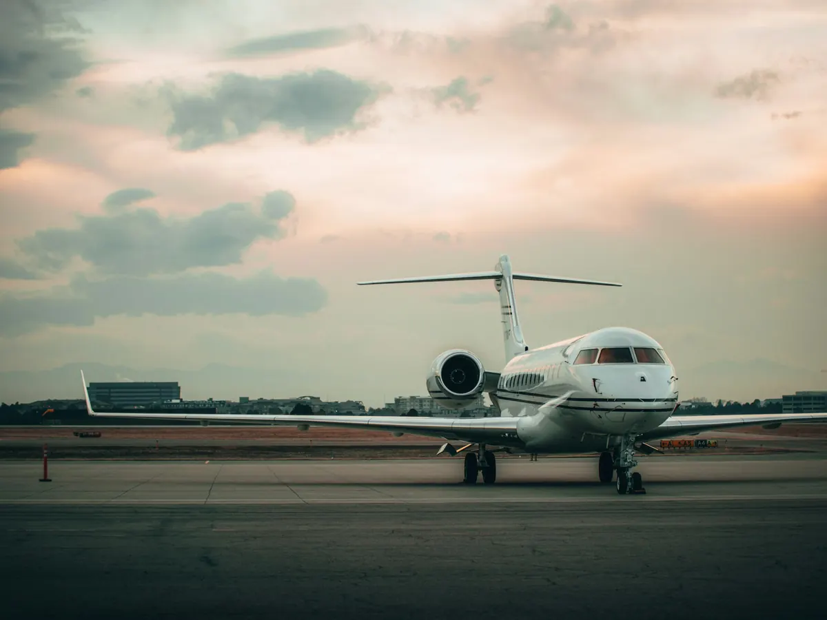 Super-midsize business jet parked on a ramp at dusk