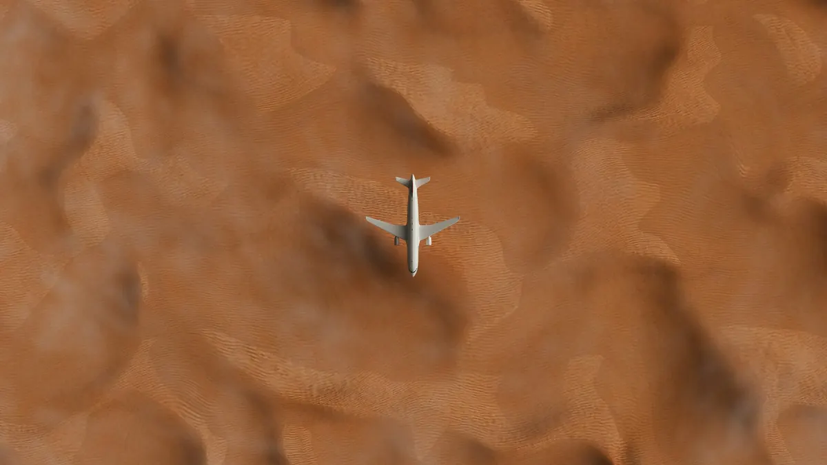 A business jet seen from above crossing rippled desert sand