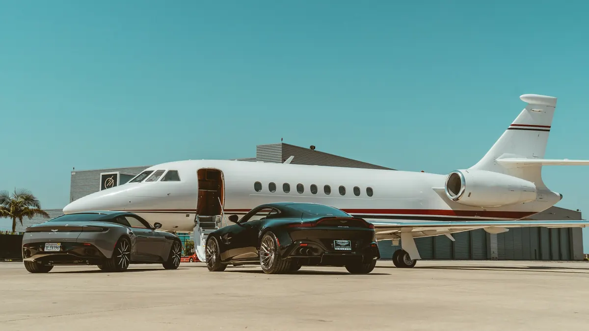 Business jet on a sunny ramp with two cars parked beside it